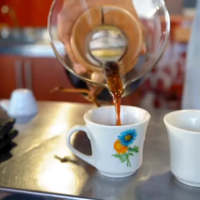 Café recién preparado sirviéndose en una taza, en una finca cafetera