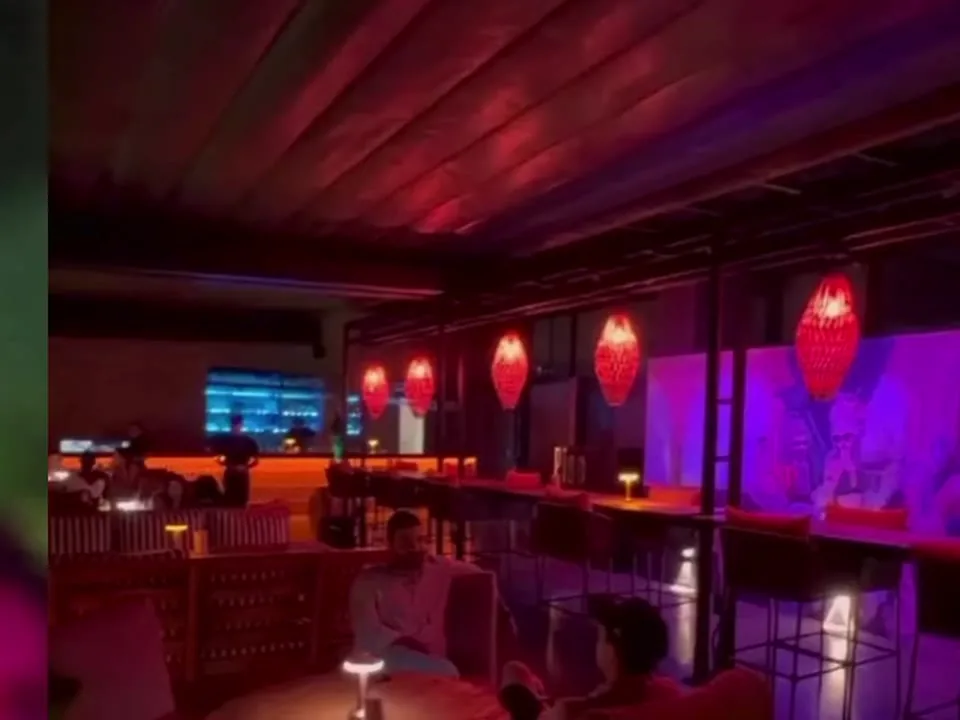Terraza de Piso 10 Rooftop de noche, con lámparas rojas y la ciudad al fondo